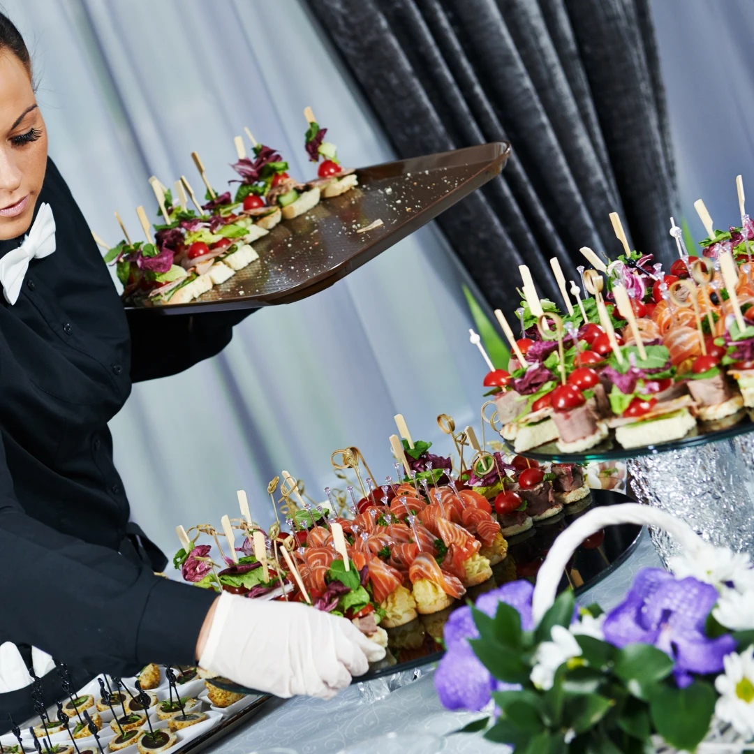 Cateringmedewerker zet hapjes klaar op een buffet